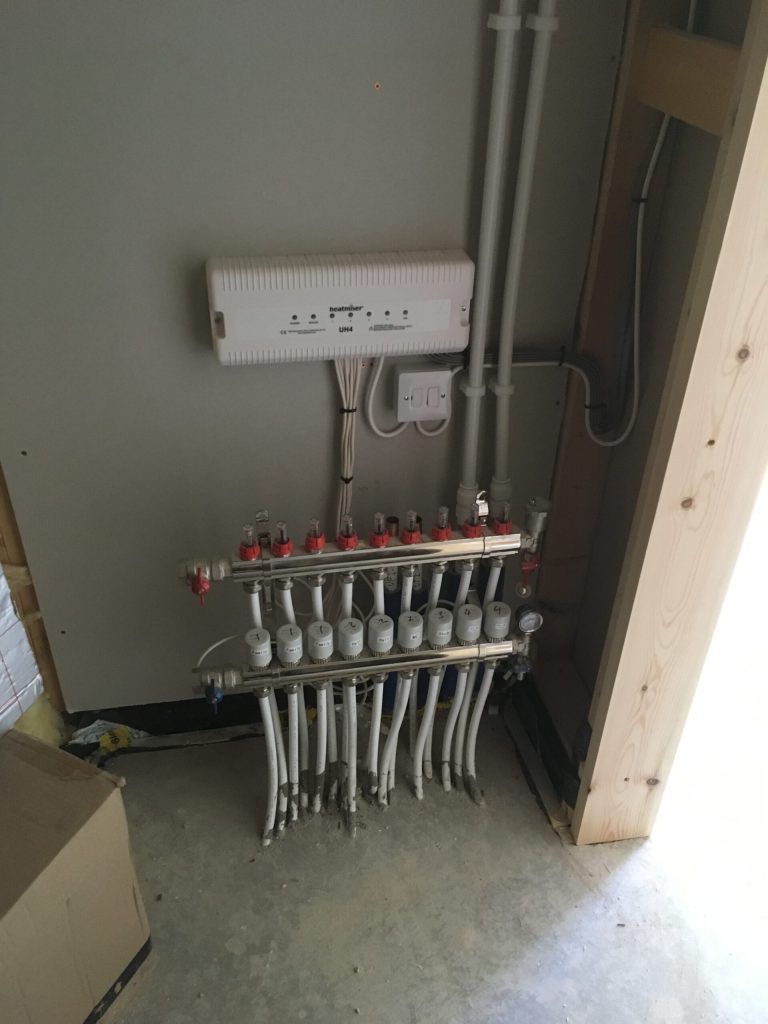 Underfloor heating manifold mounted on a wall