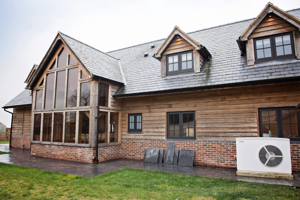 Timber-clad house with an air source heat pump installed outside