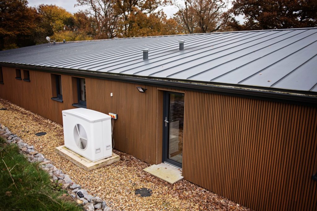Air source heat pump beside a single-storey timber-clad building