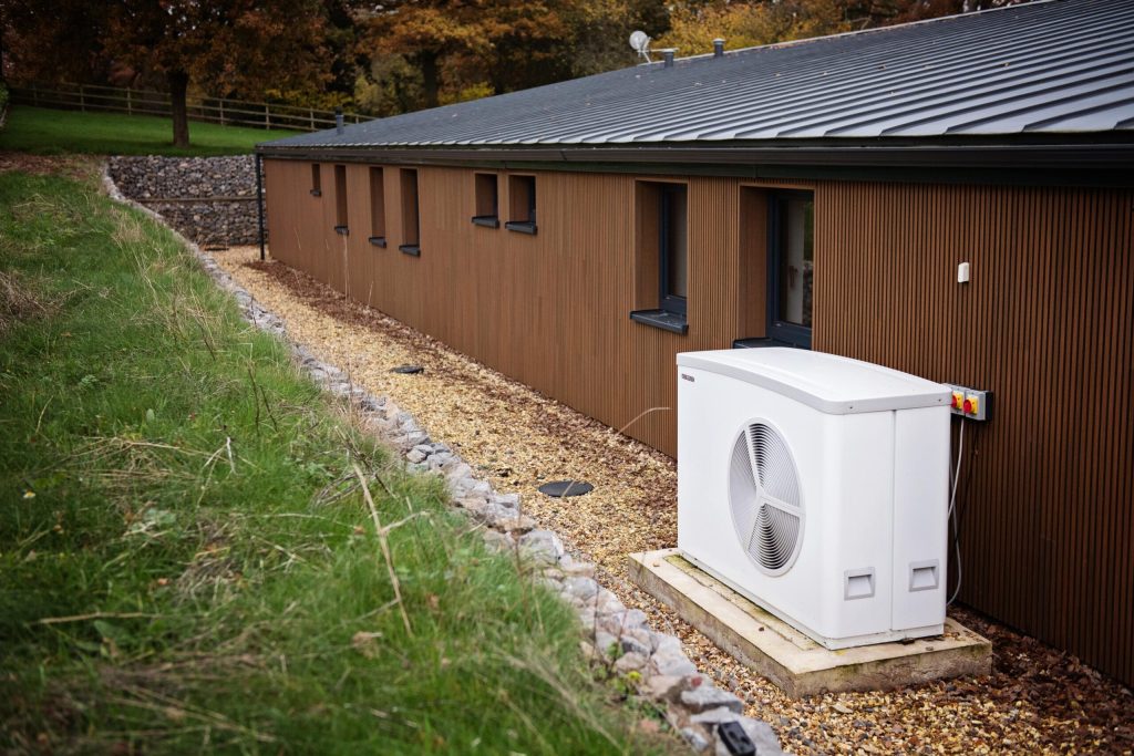 Air source heat pump beside a timber-clad building
