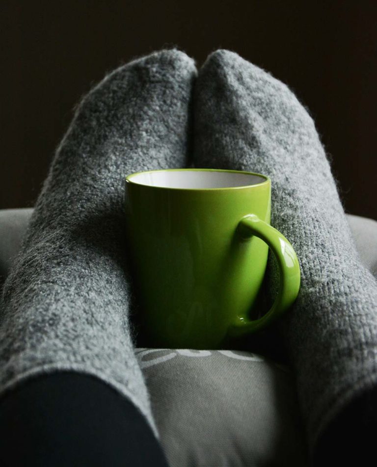 Keeping warm at home- image shows cosy socks and a mug