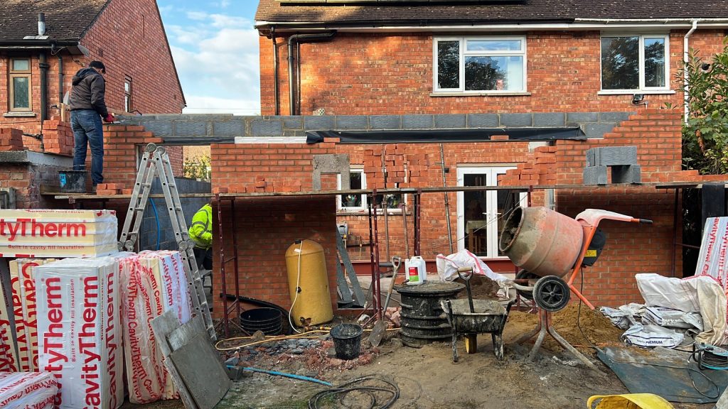 Rear garden of a brick house during a heat pump installation