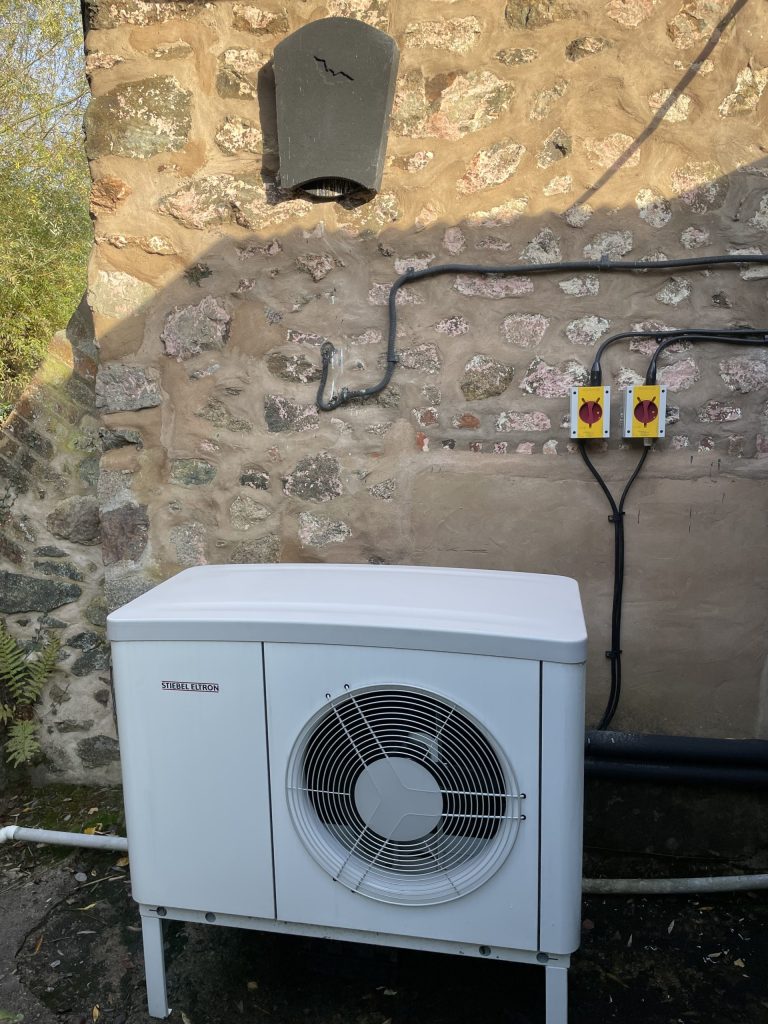 Air source heat pump installed against a stone wall