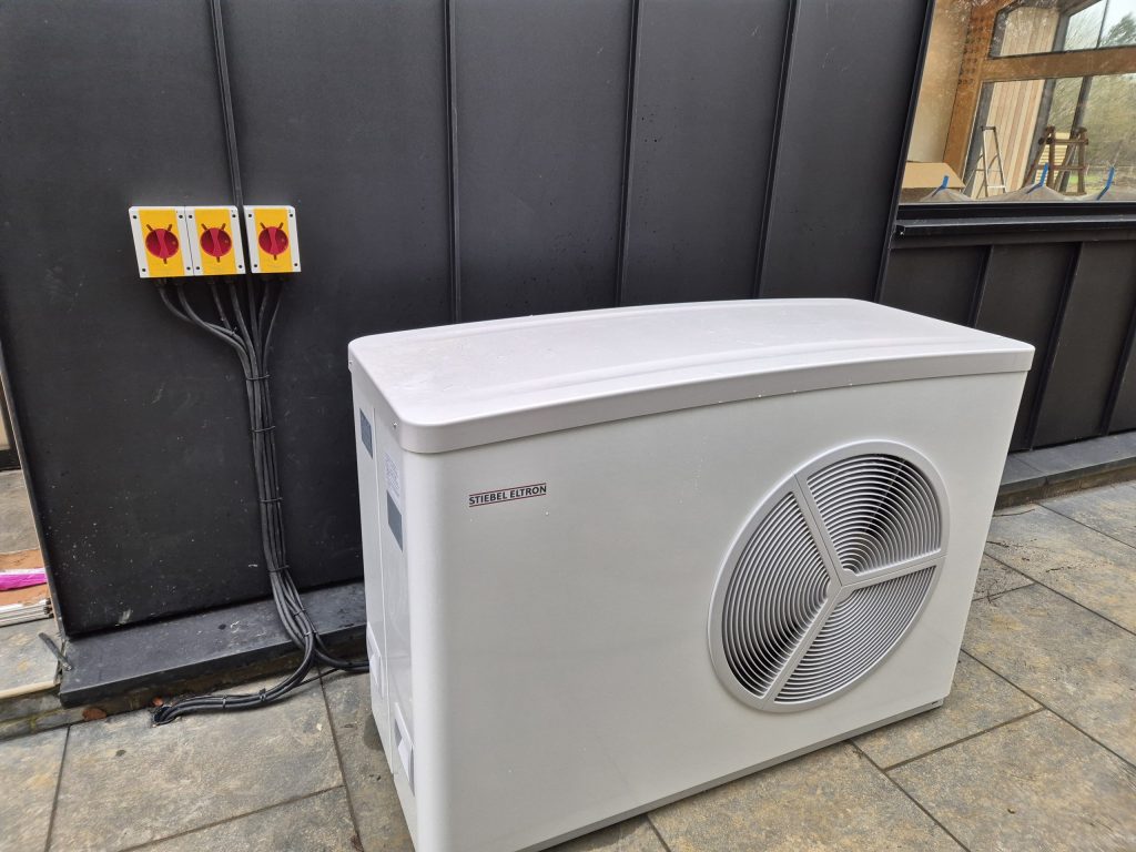 Stiebel Eltron air source heat pump against dark timber cladding